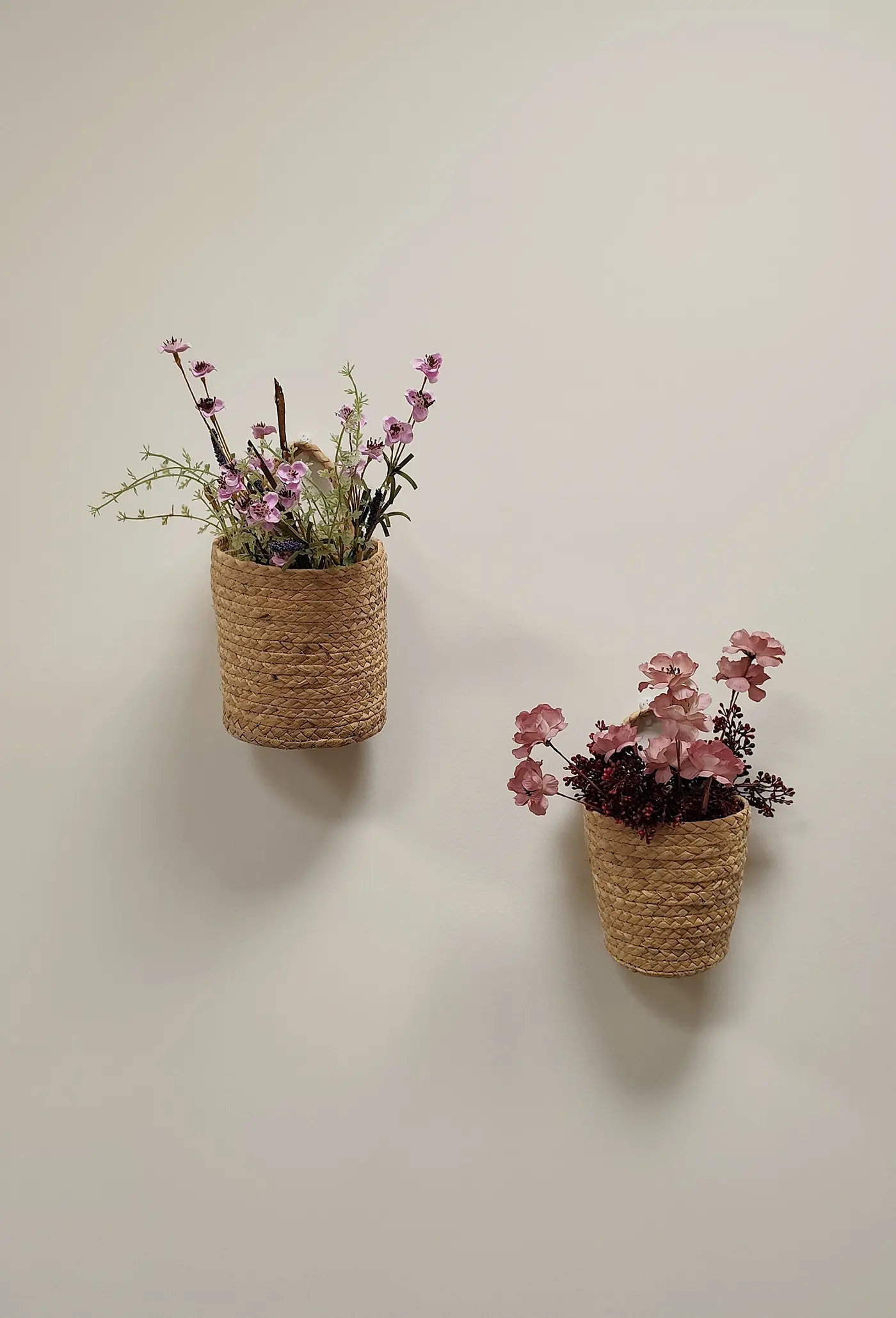 Dos cestas de fibra con flores colgadas en la pared