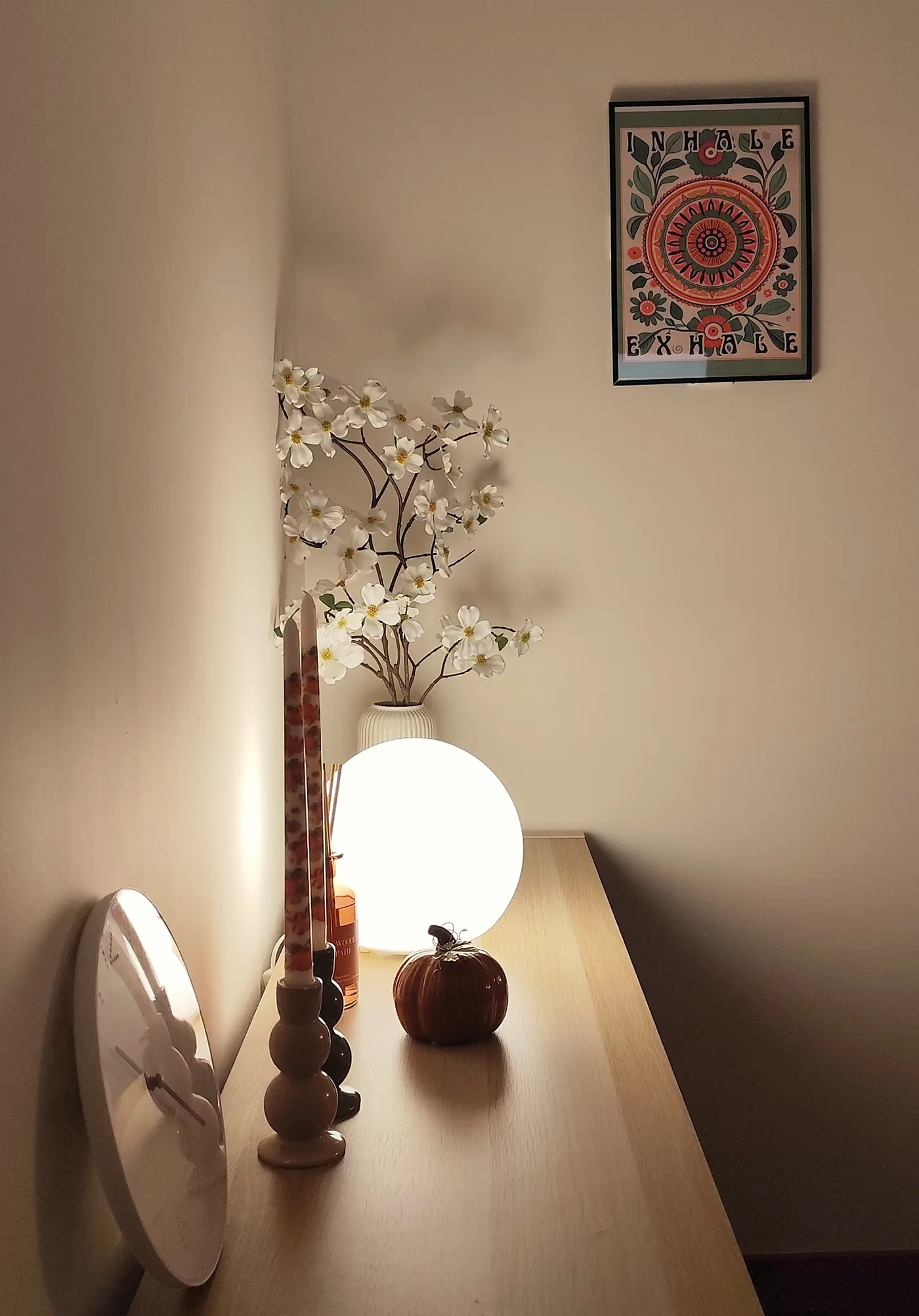 Estantería con flores, velas y una lámpara esférica