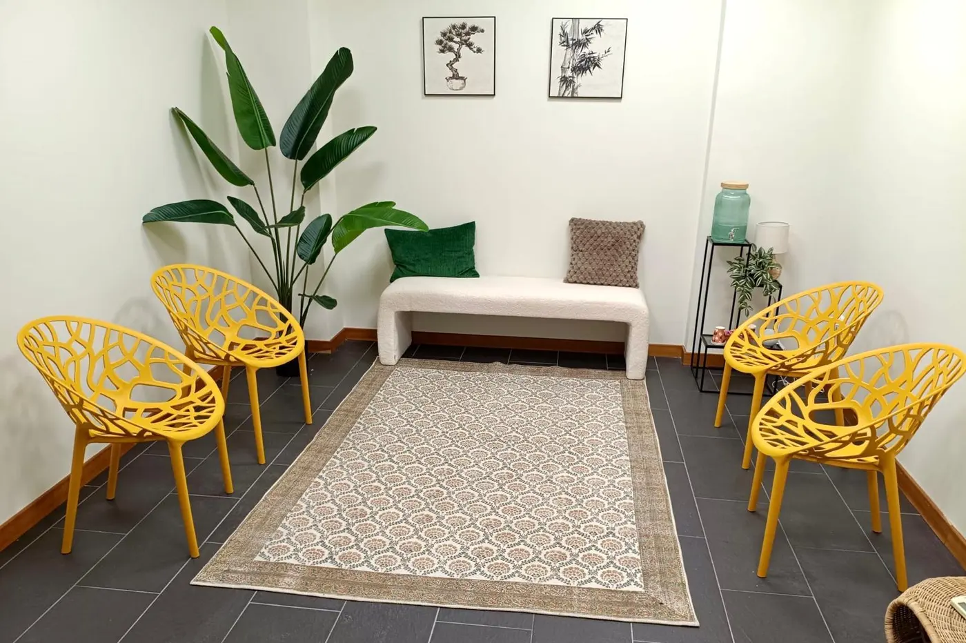 La sala de espera, con butacas amarillas, banco y plantas naturales